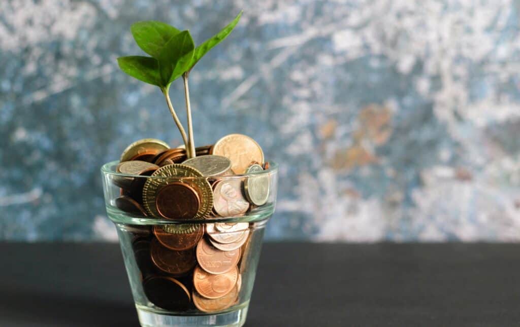 image of coins in a glass pot with a plant growing out of it